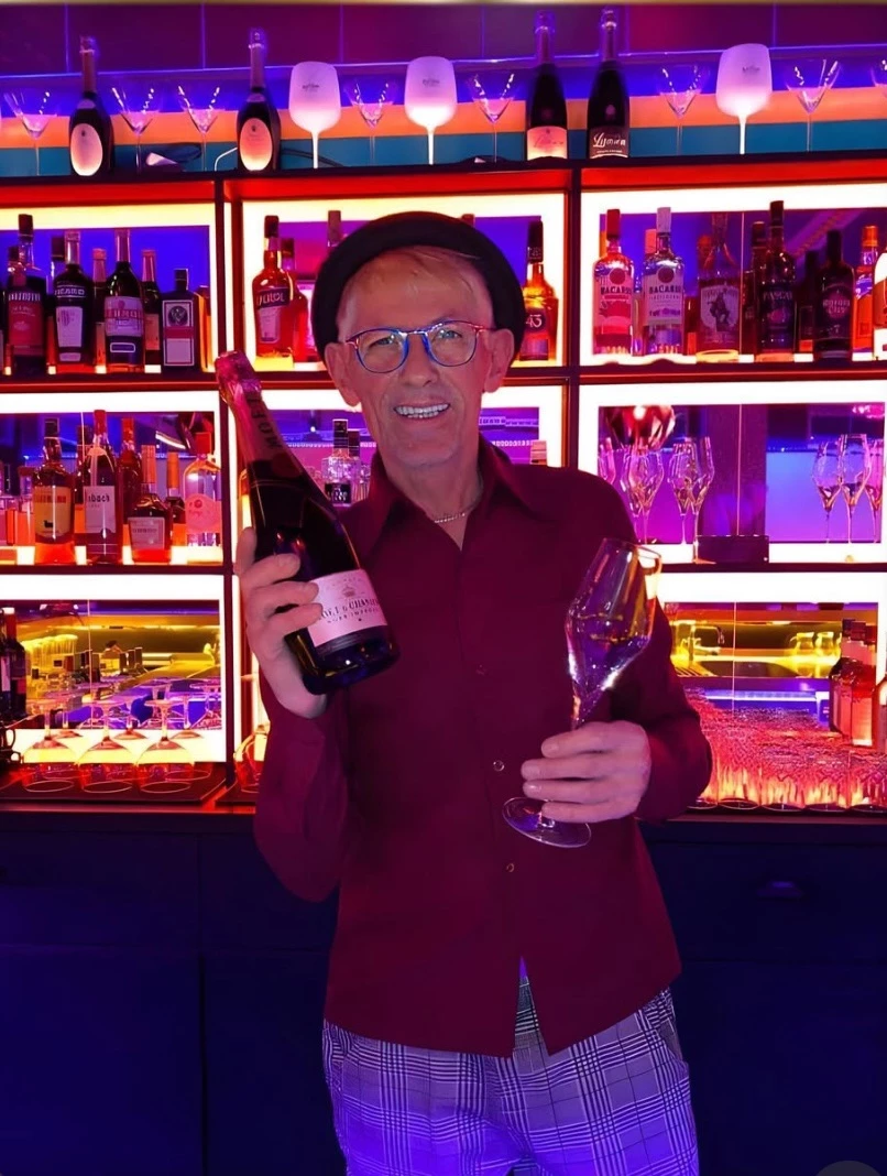 Ronny hinter der Bar mit einer Flasche Champagner